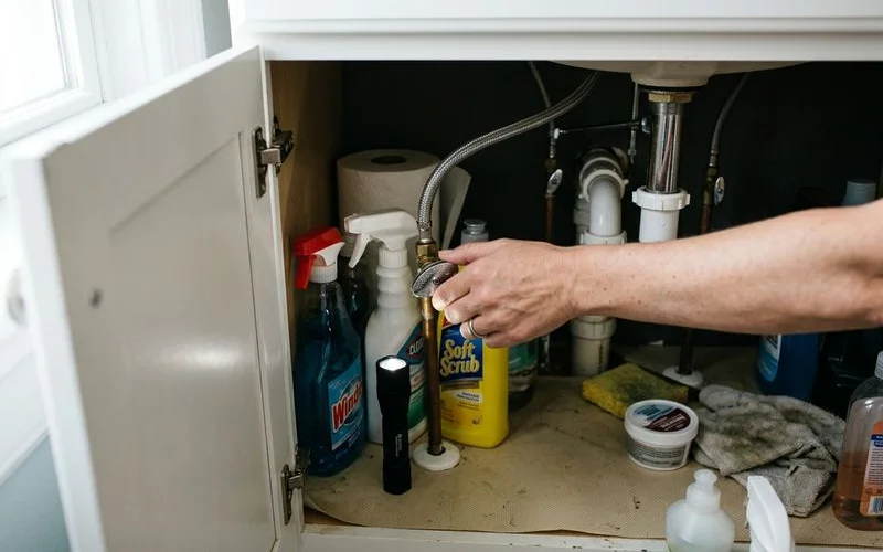 Angle stop shutoff valve under a bathroom sink being turned closed