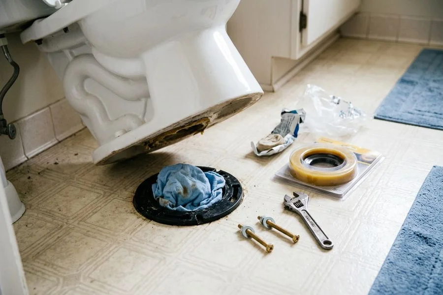 New wax ring and closet bolts laid out beside a lifted toilet