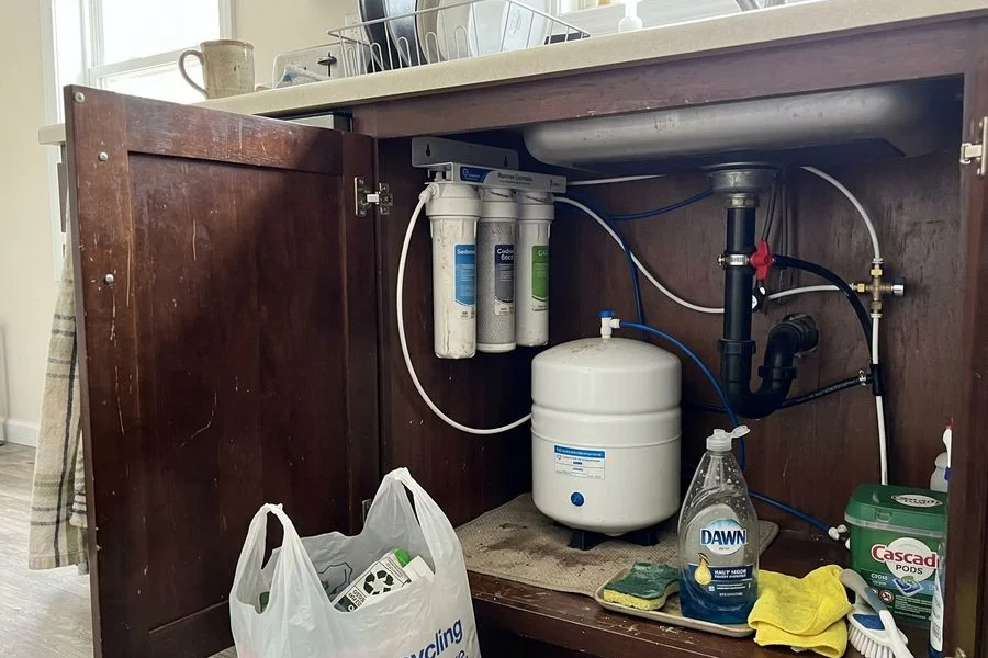 Under-sink reverse osmosis unit with filter stages and storage tank in a kitchen cabinet